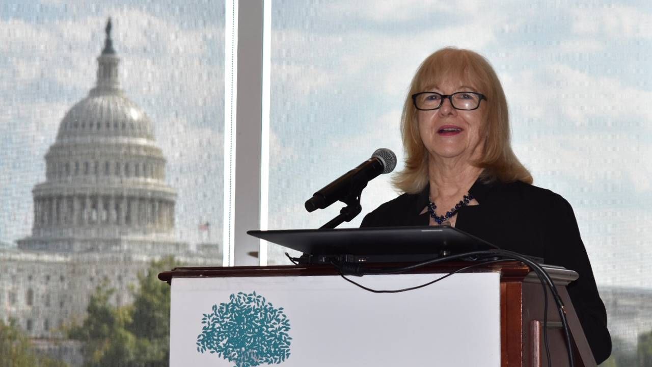 A woman standing up at a podium making a speech. Next Avenue, women retirement security