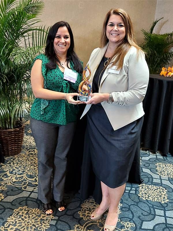 Two women standing holding an award together. Next Avenue, older workers, reckoning