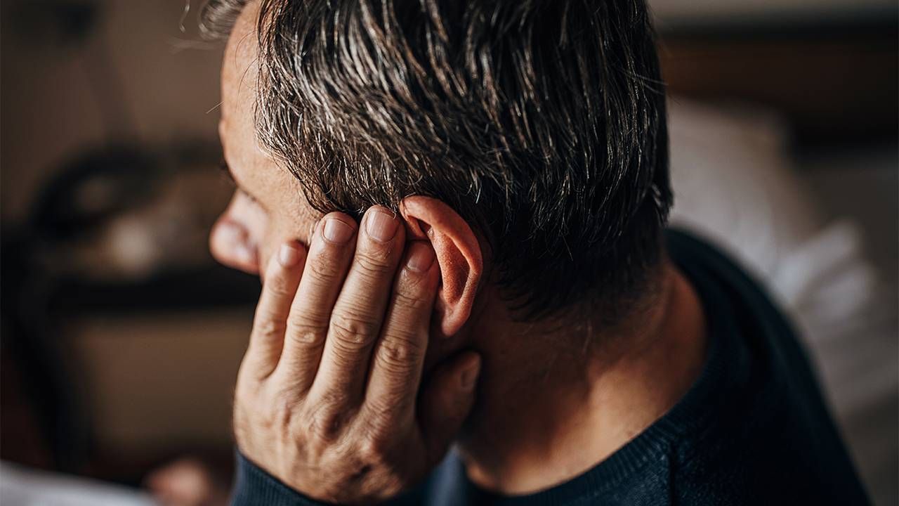 A man touching his ear after hearing ringing in his ear or tinnitus. Next Avenue