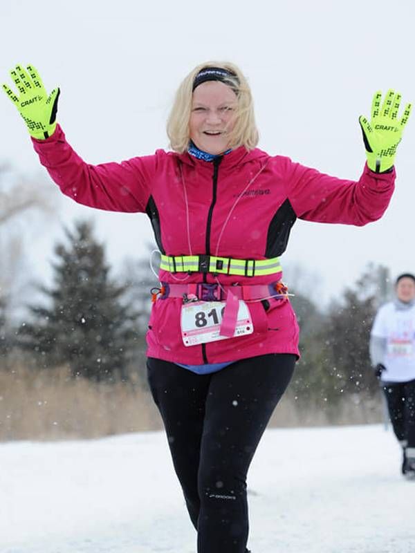 A woman running outside in the snow with her hands in the air. Next Avenue, running middle age