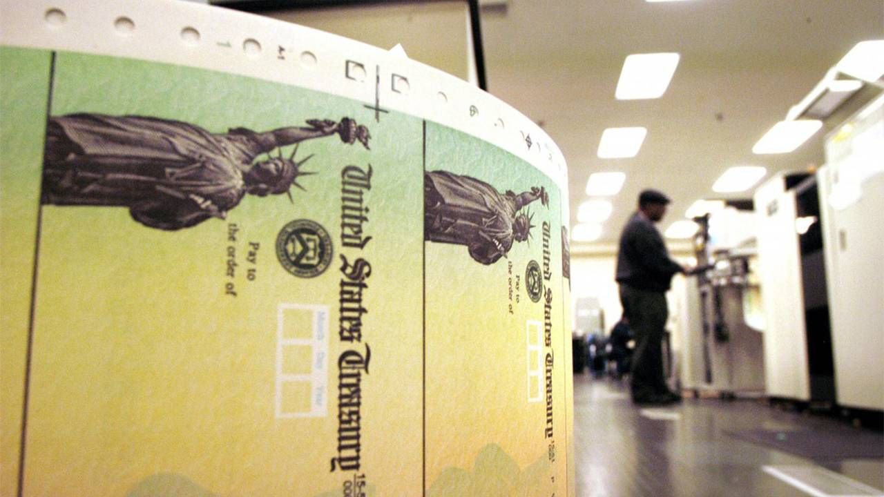 A roll of social security checks and a man standing at a counter for his social security statement. Next Avenue