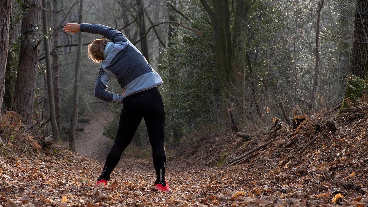 A person stretching outside on a trail. Next Avenue