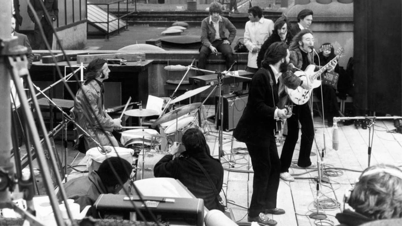 A black and white photo of the Beatles performing on a roof in their last concert together. Next Avenue, Get Back, Peter Jackson