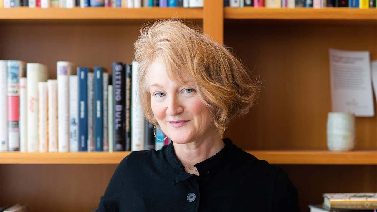 Krista Tippitt smiling while standing in front of a bookshelf. Next Avenue, on being