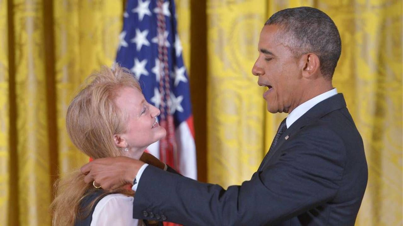 Krista Tippett standing in front of Pres. Obama while he's placing a medal around her neck. Next Avenue, on being