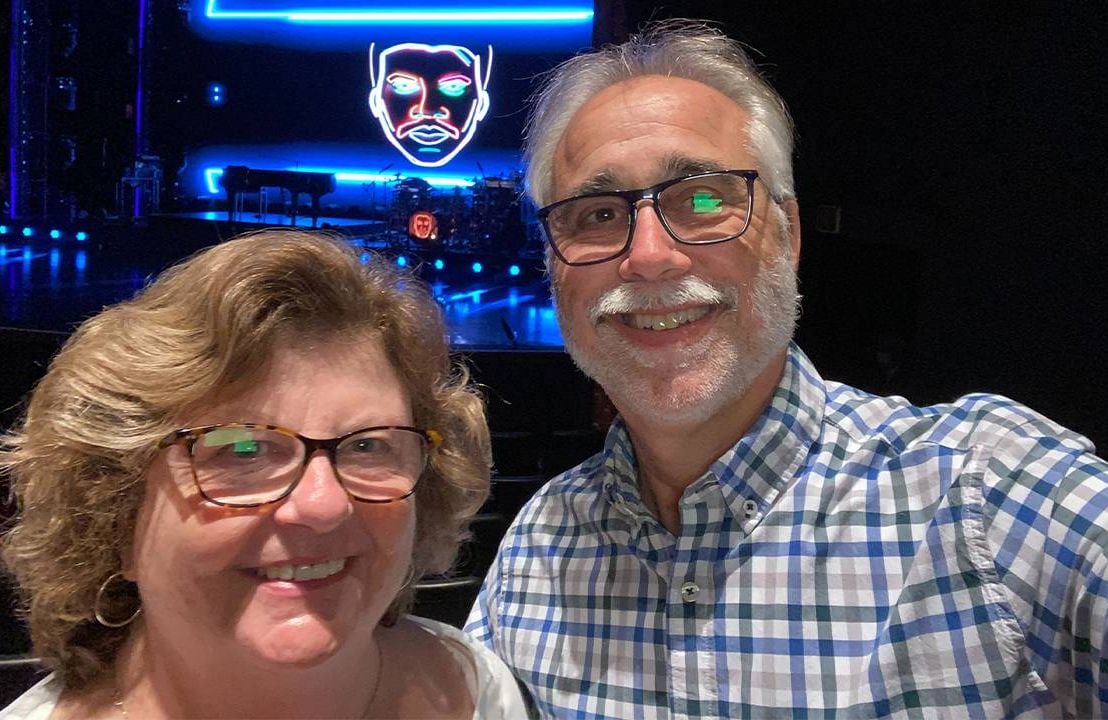 A couple smiling in front of a glowing stage. living with Alzheimer's, Next Avenue