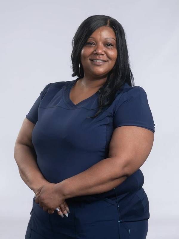 A woman wearing scrubs smiles at the camera. Next Avenue nursing homes, staff shortages