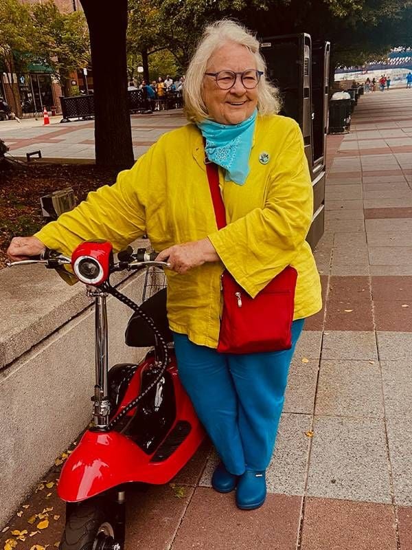 An older adult wearing colorful clothing getting on a moped. Next Avenue, ageism doctors nurses