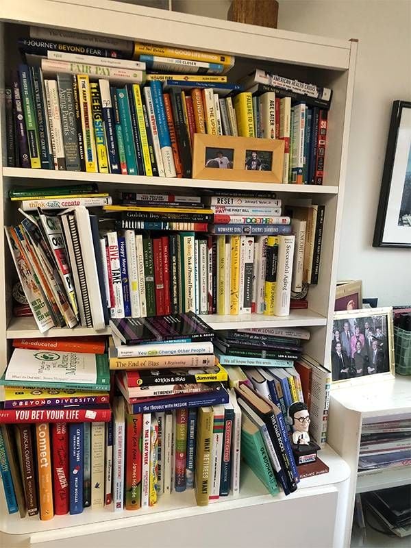 A white bookshelf overstuffed with books. Next Avenue
