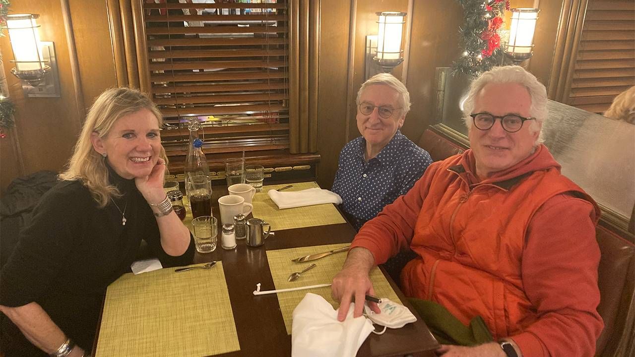 Three people smiling and sitting down for lunch at a restaurant. Next Avenue