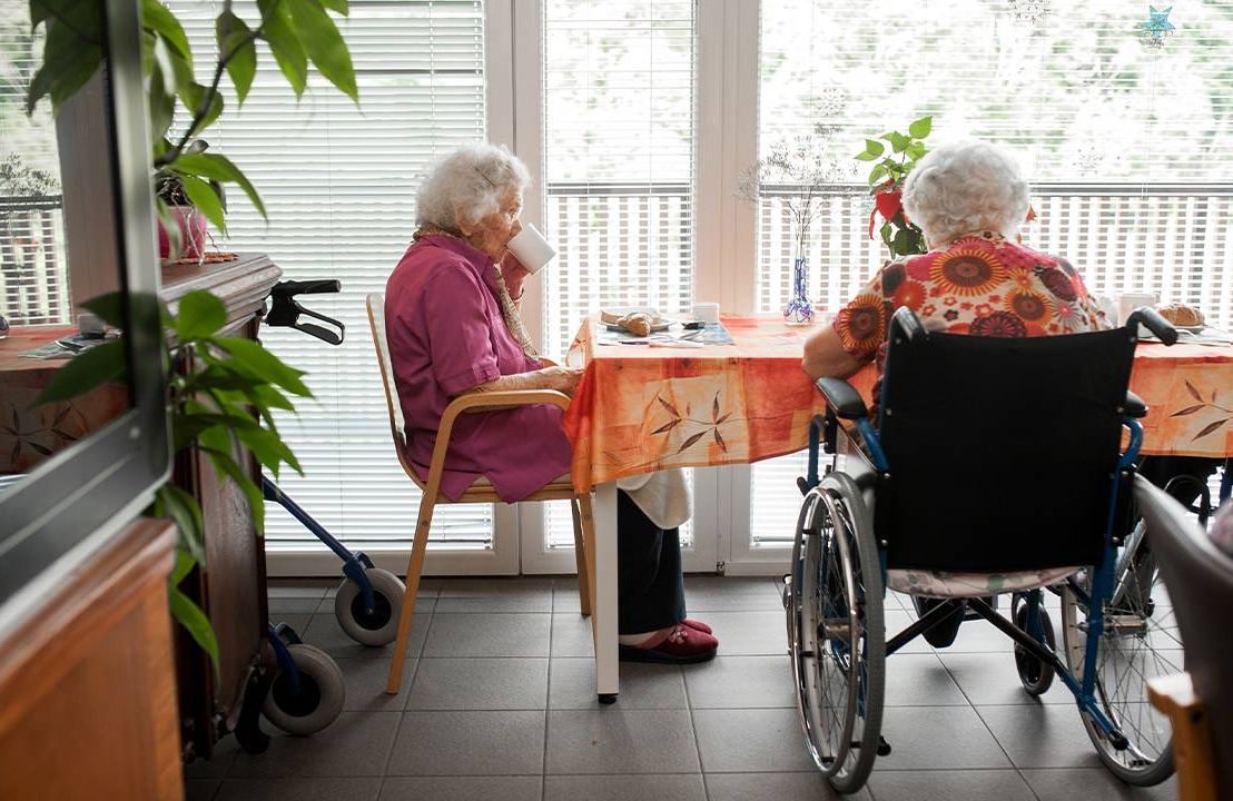 Two older adults sitting at a breakfast table in a long-term care facility. Next Avenue, Elder fraud, elder financial fraud, long term care