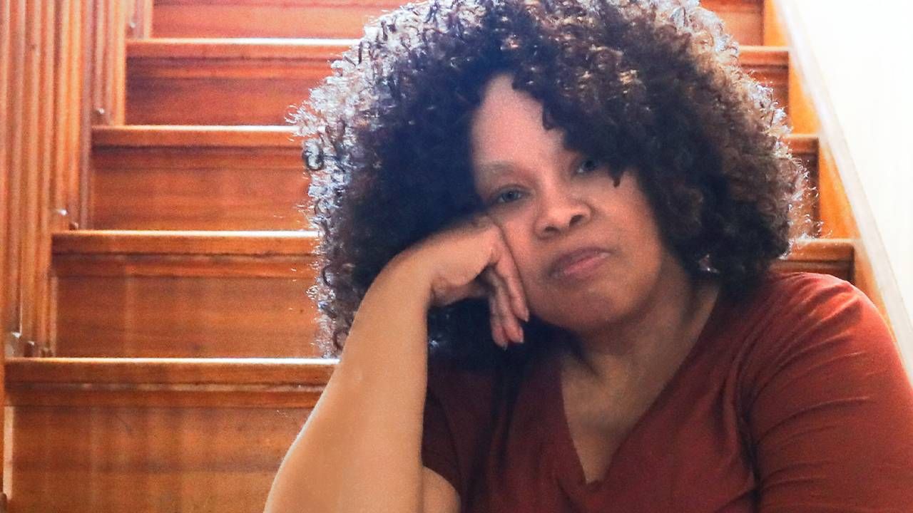 A women with curly hair sitting on a staircase in her home. Next Avenue,