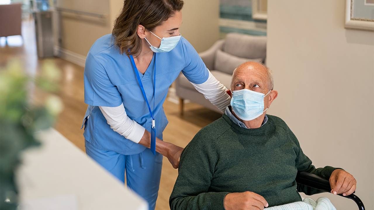 A nurse helping a nursing home patient in a wheelchair. Next Avenue