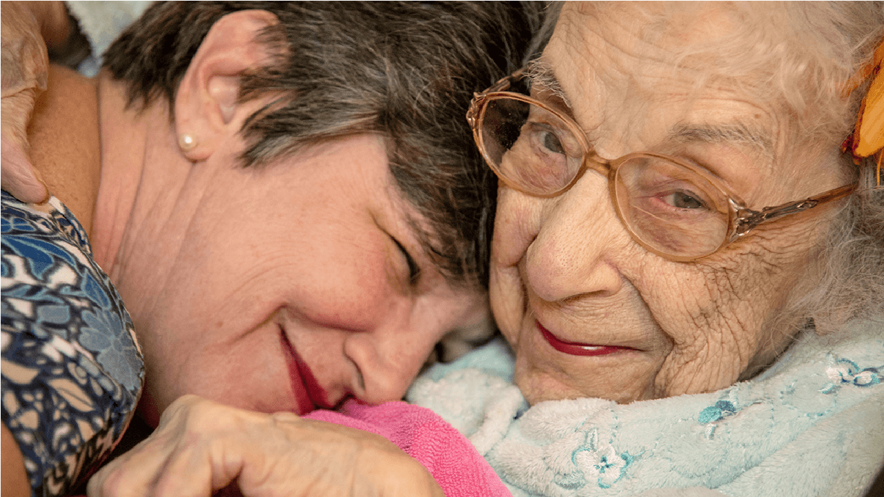 Two older adults embracing, smiling anf laughing. Next Avenue