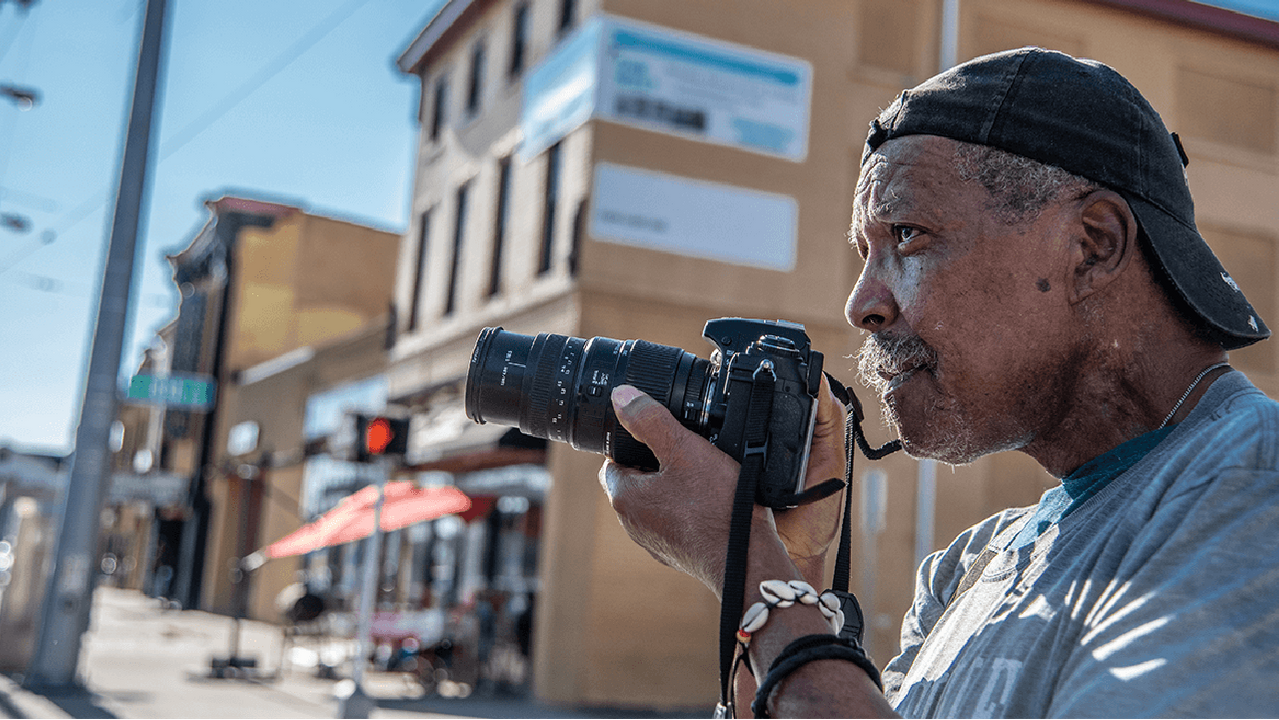 A man taking photos on a street. Next Avenue