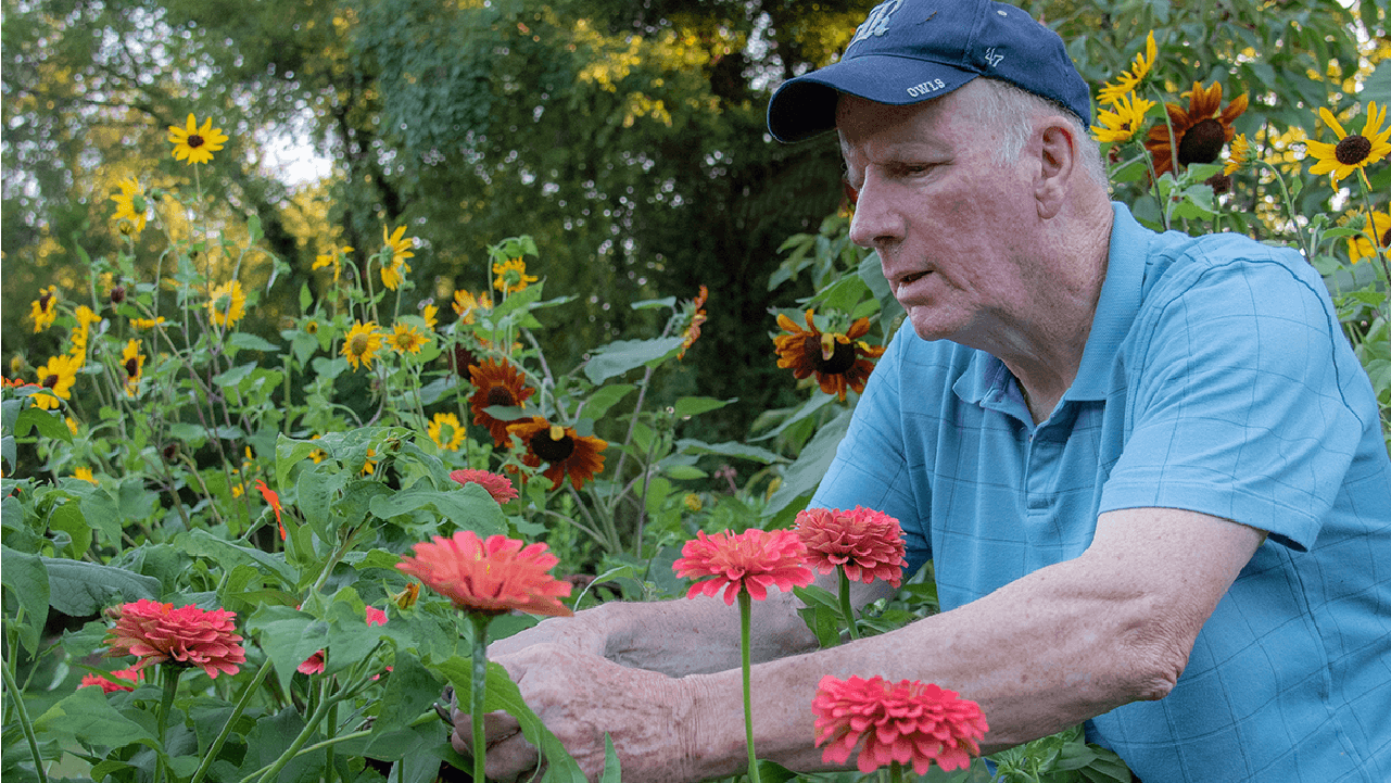 A man tending to flowers in a garden. Next Avenue