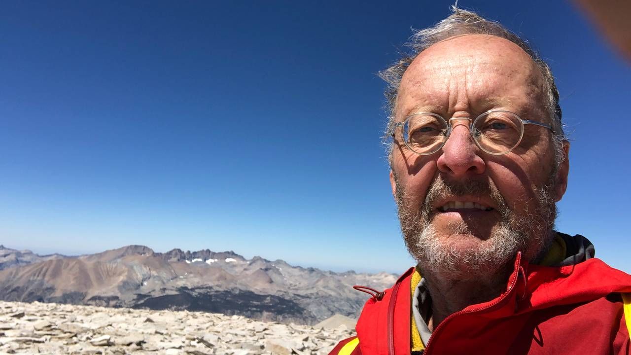 A man wearing a red jacket standing in front of a mountain range. Next Avenue, kidney transplants information