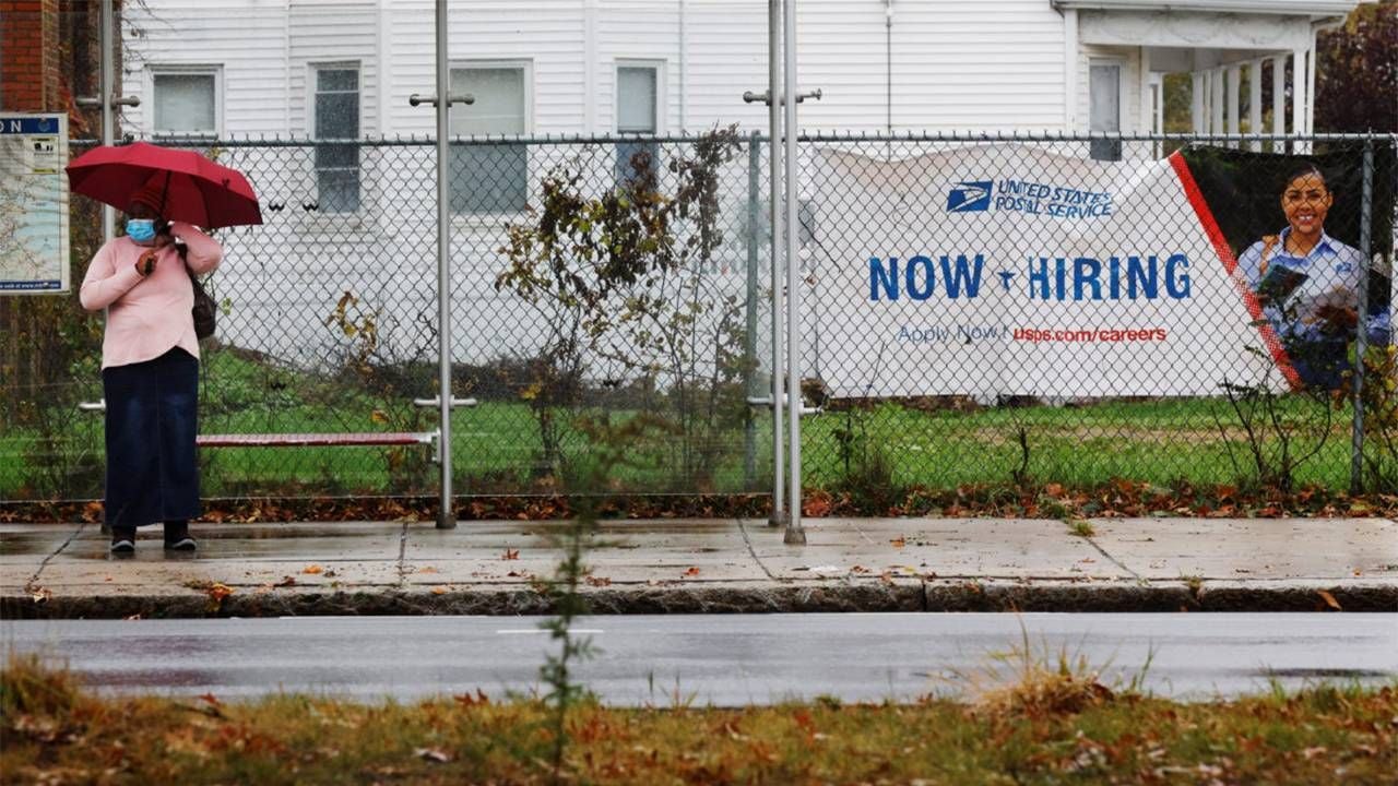 An older adult waiting for the bus next to a now hiring sign. Next Avenue, older workers not getting hired