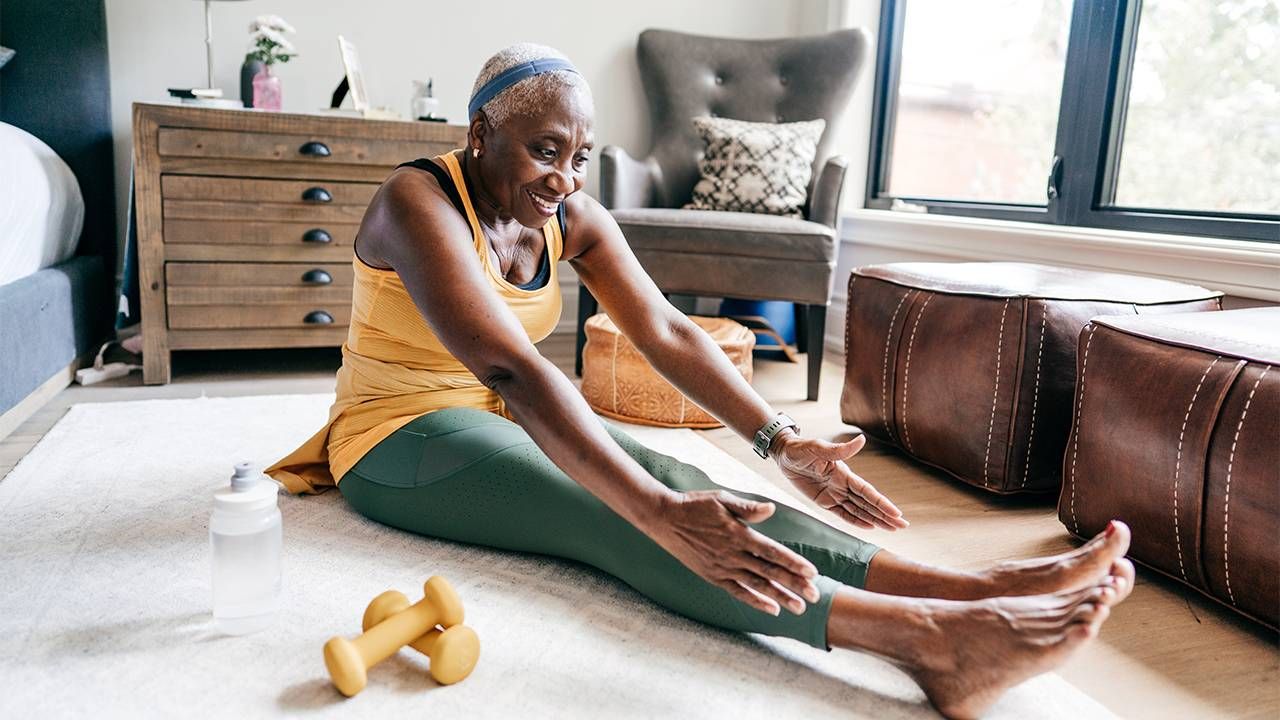 An older woman sitting on the ground doing stretches. Next Avenue, posture tips exercises