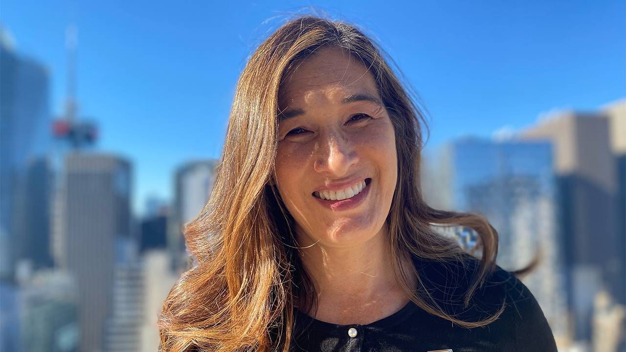 A woman standing in front of a city skyline smiling. Next Avenue, inflation, fixed income retirees