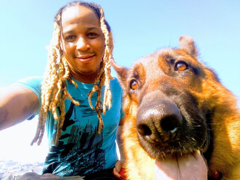 A person with dreadlocks smiling and posing with a german shepherd dog. Next Avenue, decision making, difficult decisions