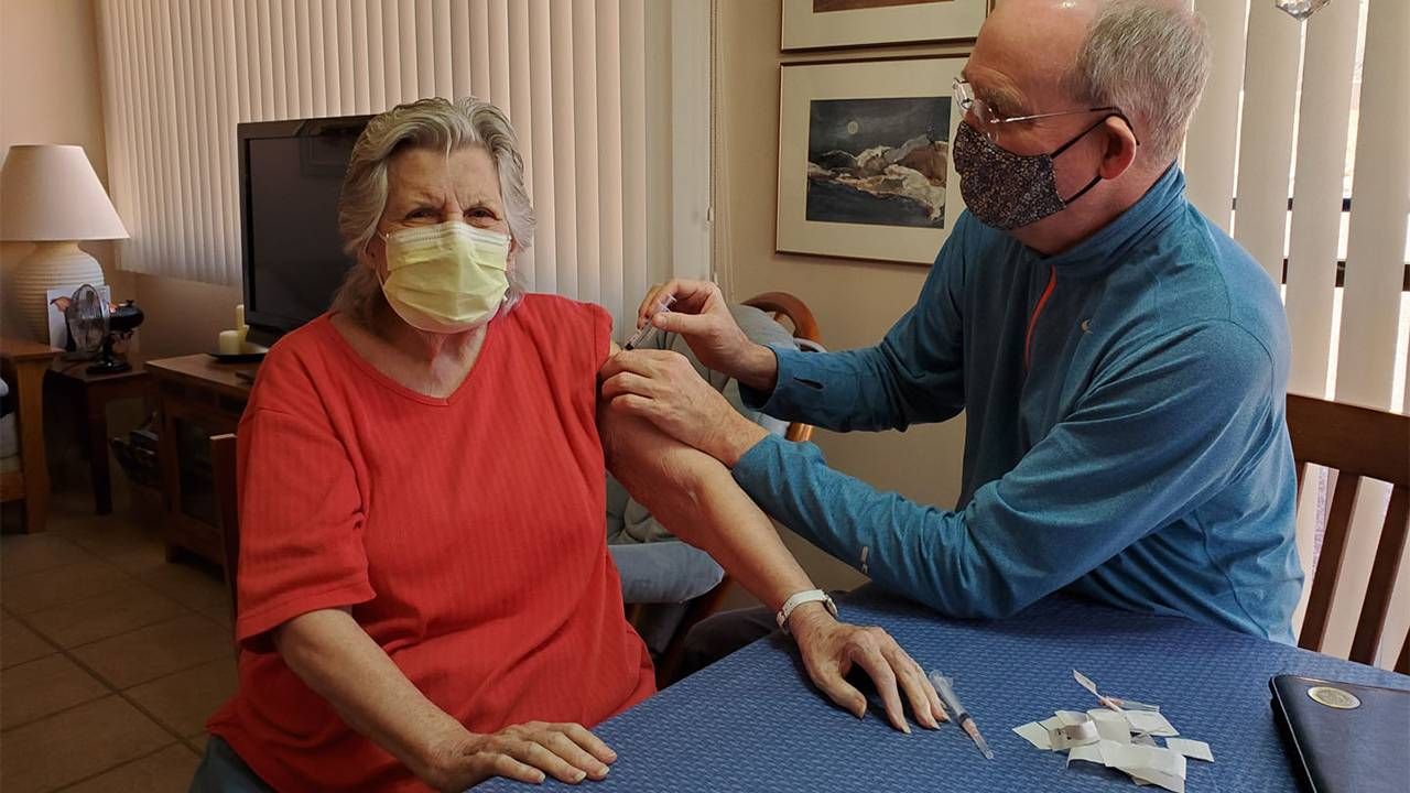 An older adult who is aging in place in a rural area getting her vaccine at home by a doctor. Next Avenue