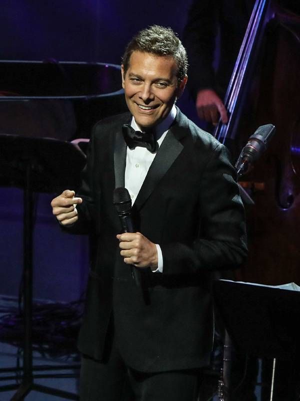 A man wearing a tuxedo singing on stage. Next Avenue, The great American Songbook, Michael Feinstein