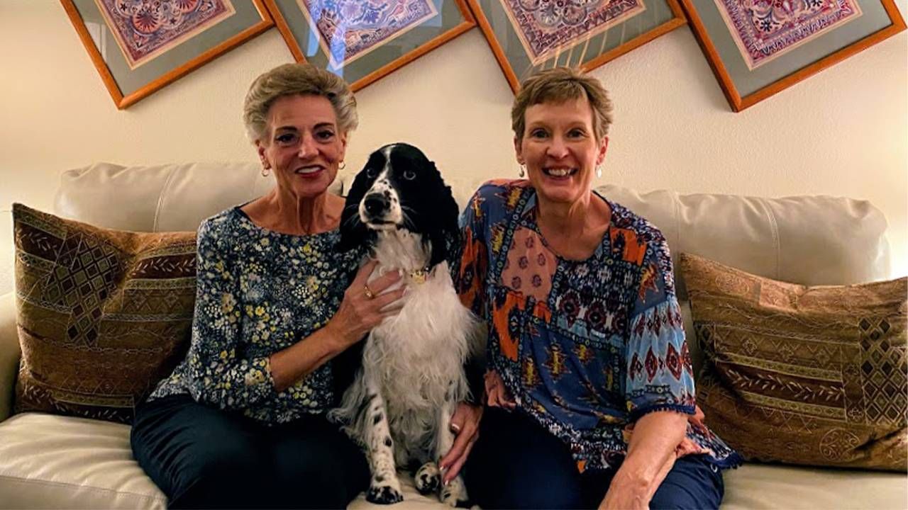 Two homesharing older adults sitting on a couch with a dog sitting between them. Next Avenue, older roommates, housing costs