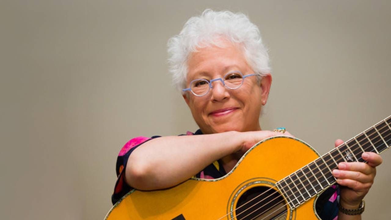 Janis Ian playing the guitar on stage. Next Avenue, The Light At The End of The Line