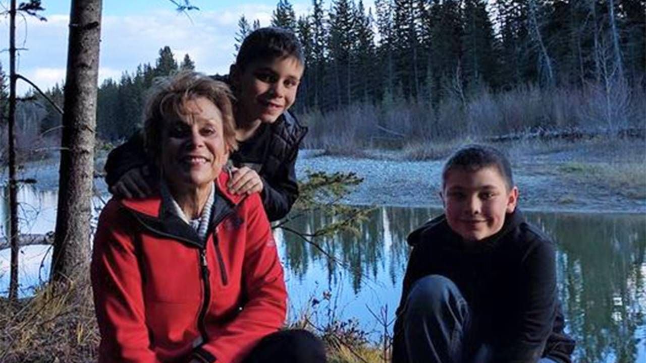 A grandmother kneeling with her two grandsons near a creek. Next Avenue