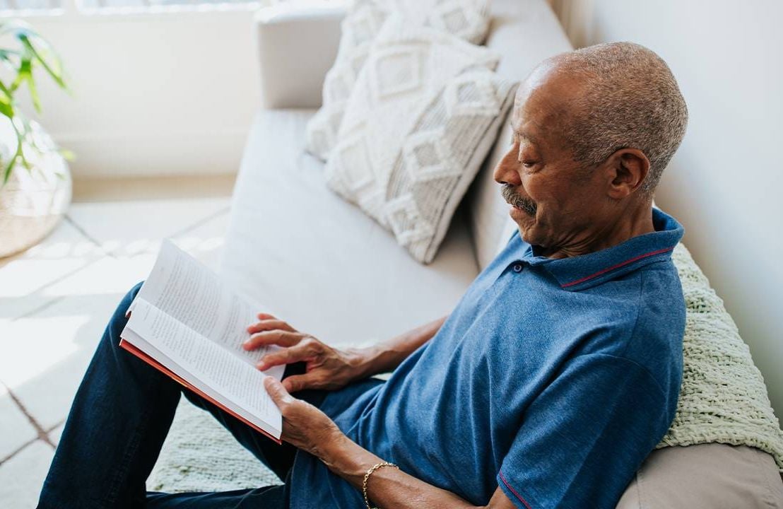 An older adult reading a money book at home. Next Avenue, money finance books
