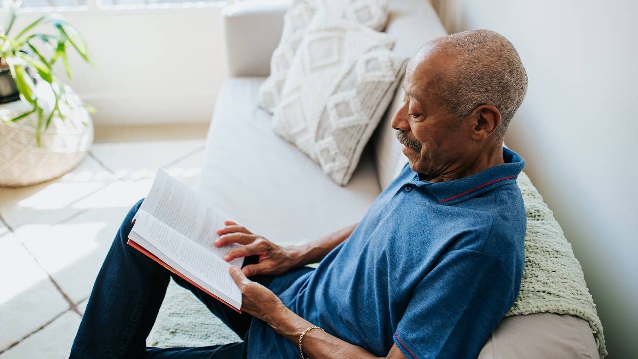 An older adult reading a money book at home. Next Avenue, money finance books