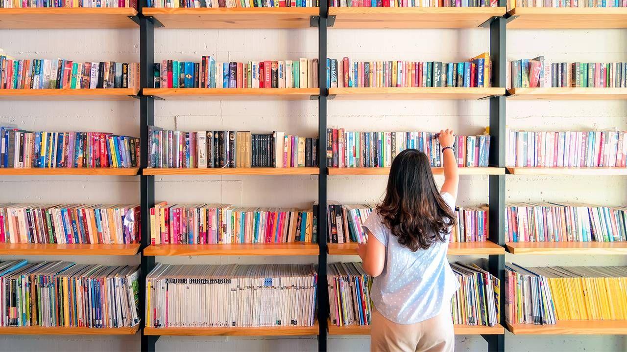 A woman standing in front of a shelf filled with picture books. Next Avenue