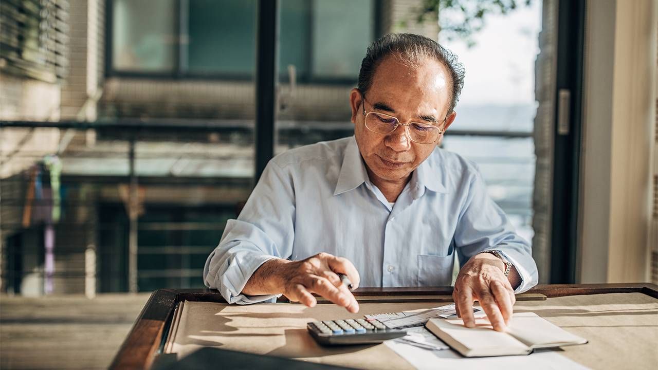 An older man calculating his personal finances at home. Next Avenue, Super Age, Finances, Money
