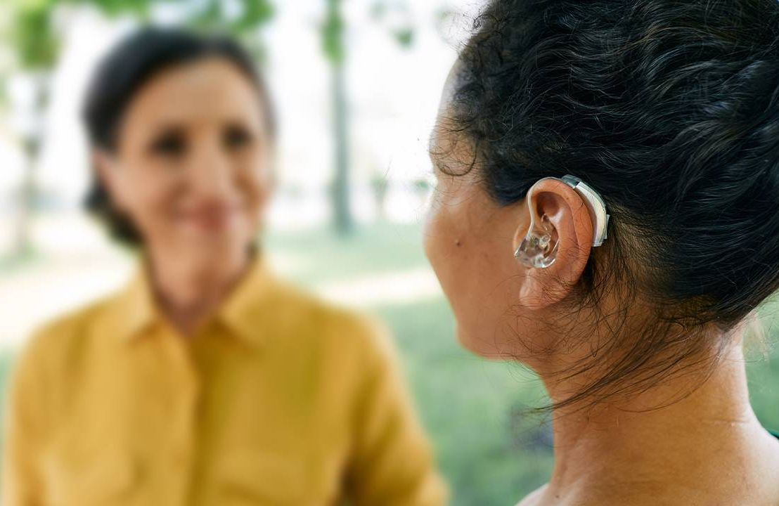 A person wearing a hearing aid outside. Next Avenue, adjusting to hearing aids