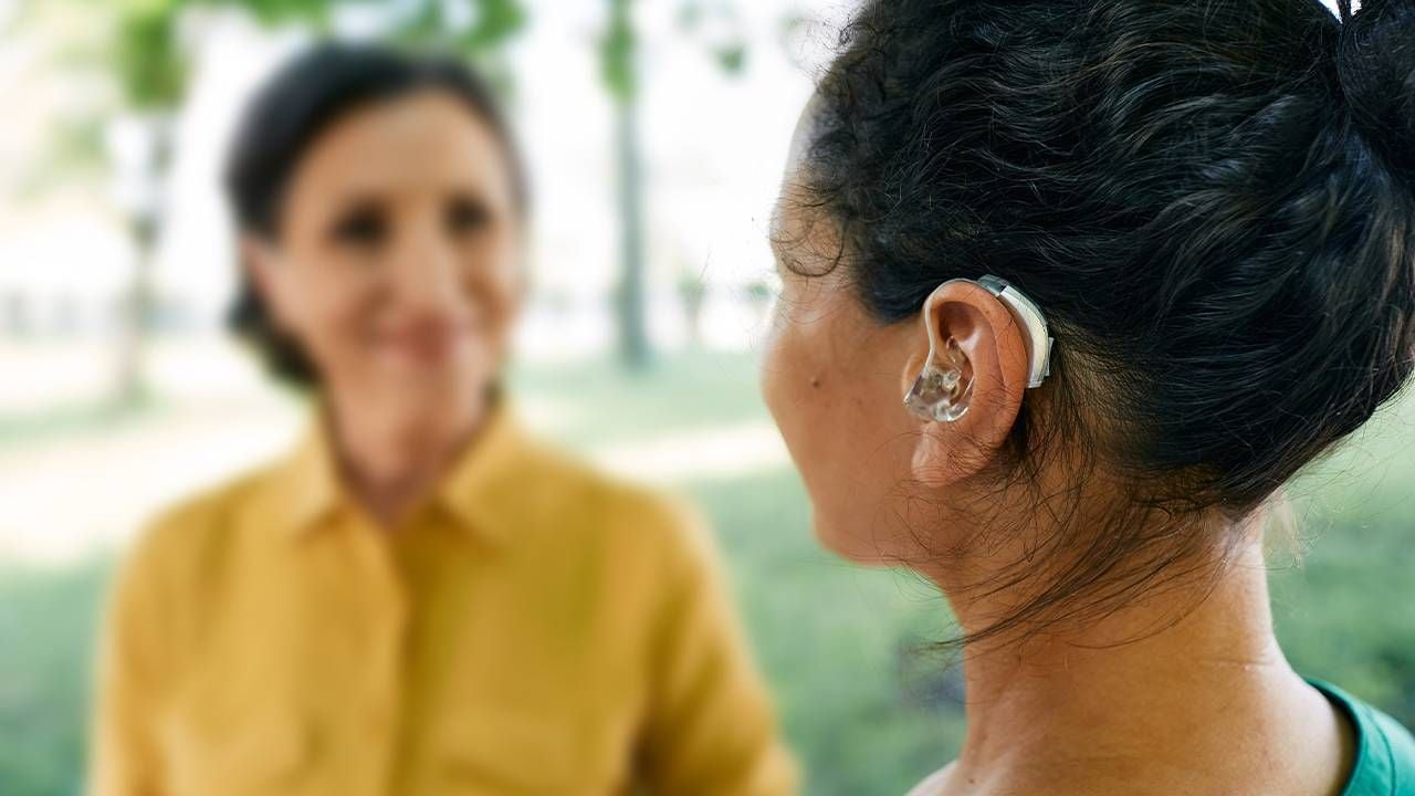 A person wearing a hearing aid outside. Next Avenue, adjusting to hearing aids