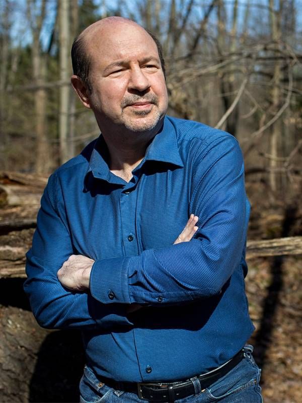 An older man standing with his arms crossed in the woods. Next Avenue, climate change, report, the new climate war