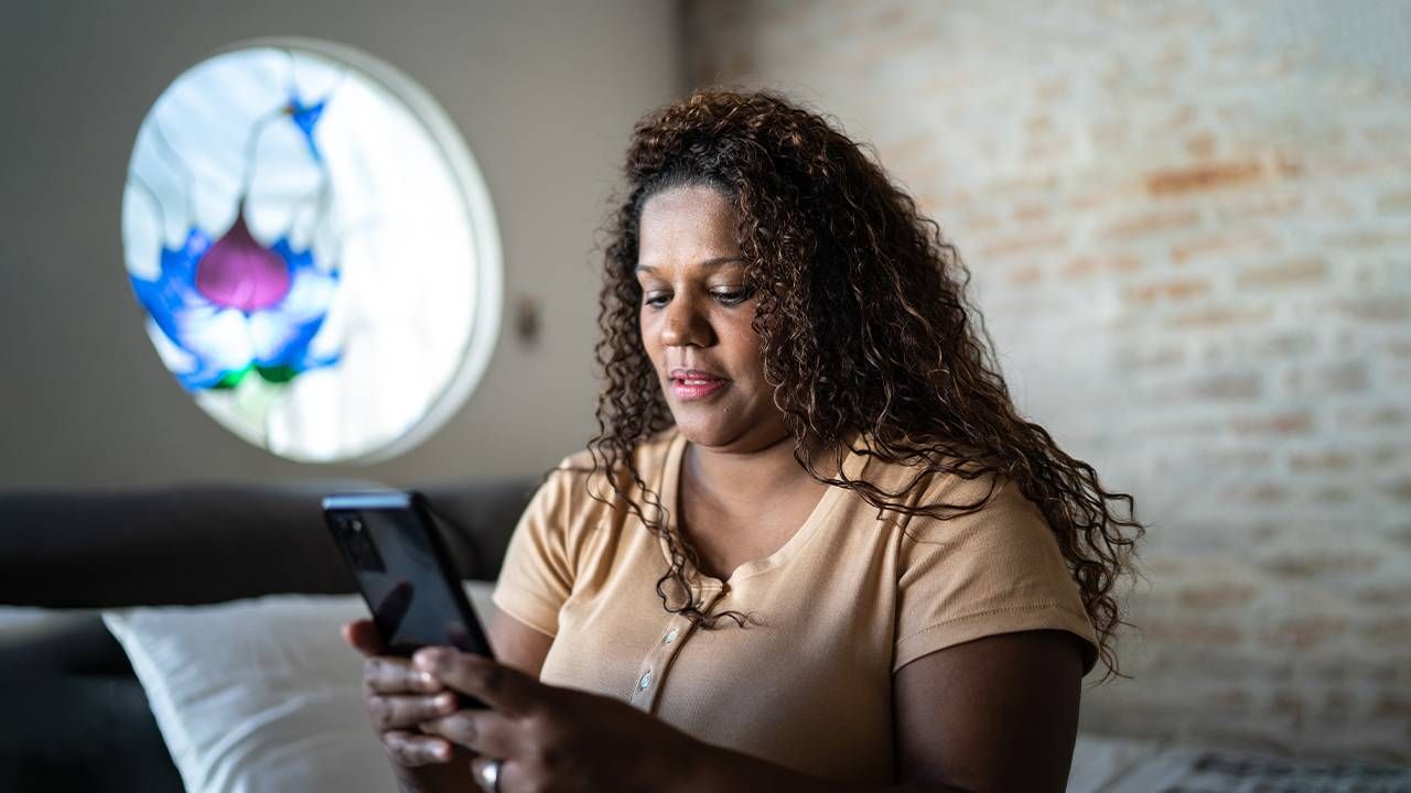 A woman sitting down googling symptoms on her phone. Next Avenue, google, diagnosis