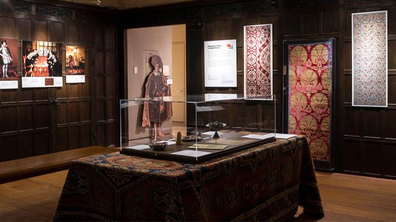 A room with wooden panel walls with turkish rugs displayed. Next Avenue, period rooms, MIA