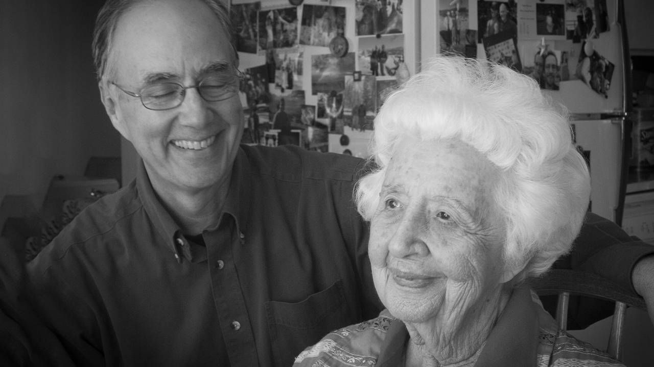 An older caregiver smiling with his mother. Next Avenue, caregiving advice, caregiving for a parent