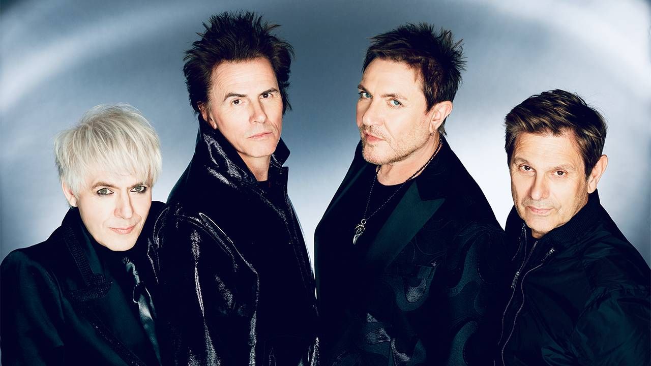 The four members of the rock band Duran Duran wearing black suits and smiling. Next Avenue