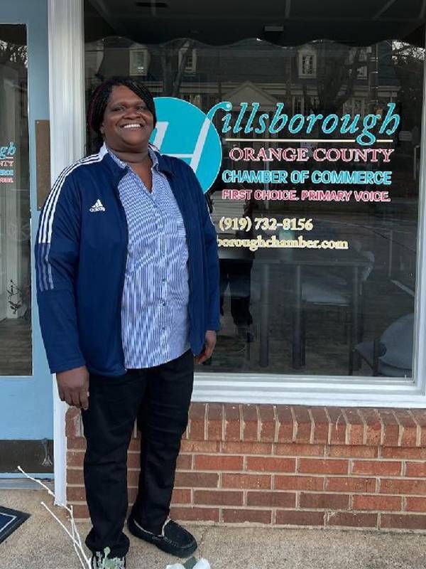 A woman standing on a sidewalk outside a chamber of commerce. Next Avenue, starting a new business