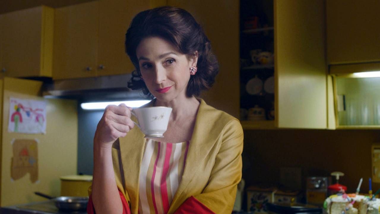 A 1950s styled kitchen with a woman holding a teacup. Next Avenue, The Marvelous Mrs. Maisel, Marin Hinkle