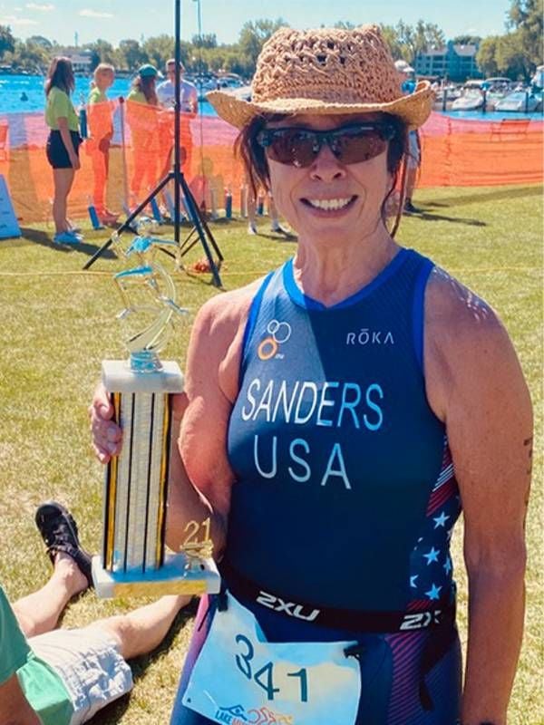 An older adult holding a triathlon trophy after finishing a race. Next Avenue, triathletes over 50