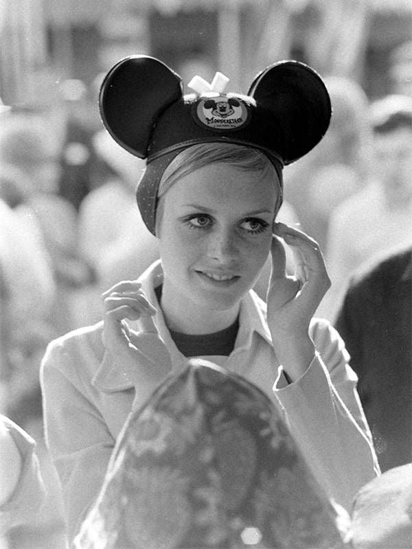 Twiggy adjusting a pair of Mickey Mouse "ears" at Dinseyland. Next Avenue, Twiggy, body image