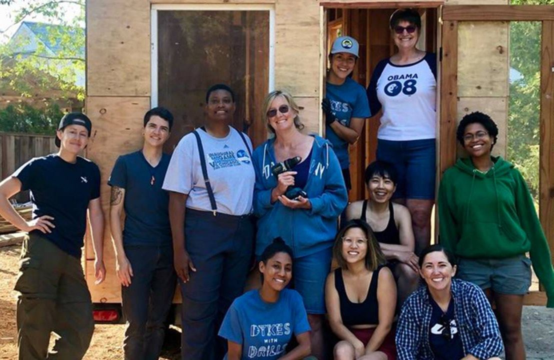 A group of people standing outside of a tiny home they just built. Next Avenue, women in construction, trades, Dykes with Drills
