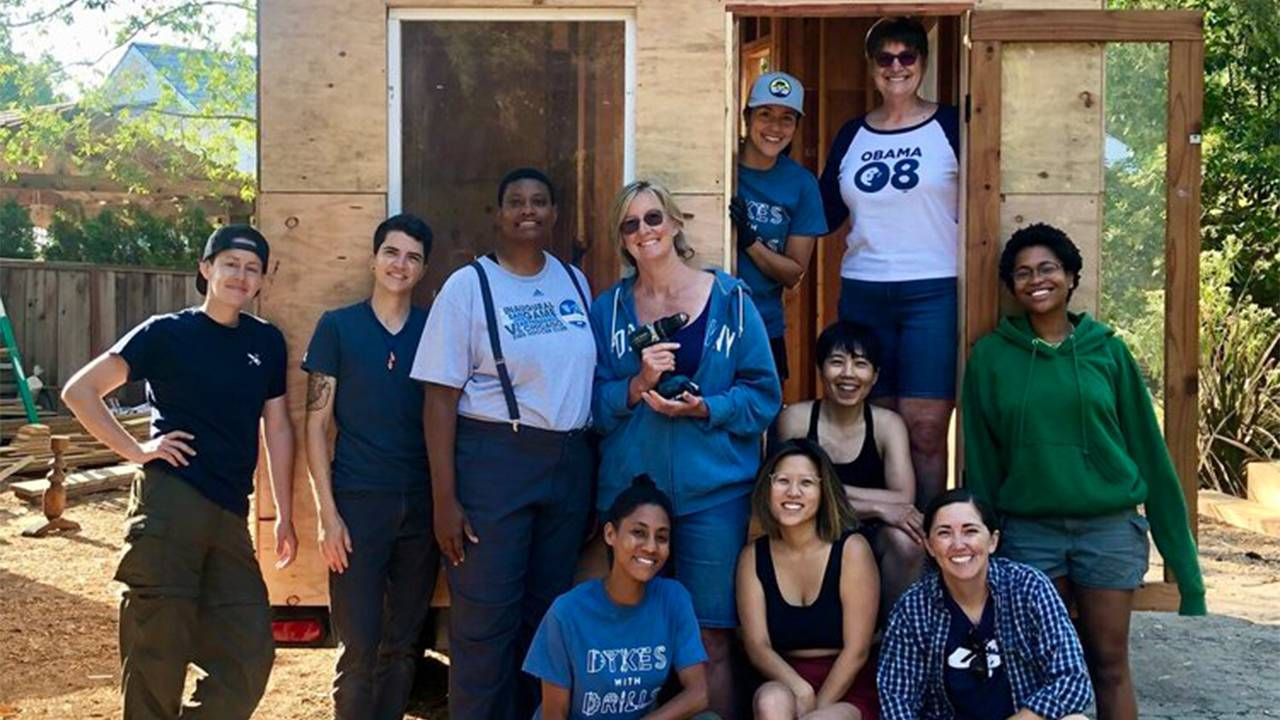 A group of people standing outside of a tiny home they just built. Next Avenue, women in construction, trades, Dykes with Drills