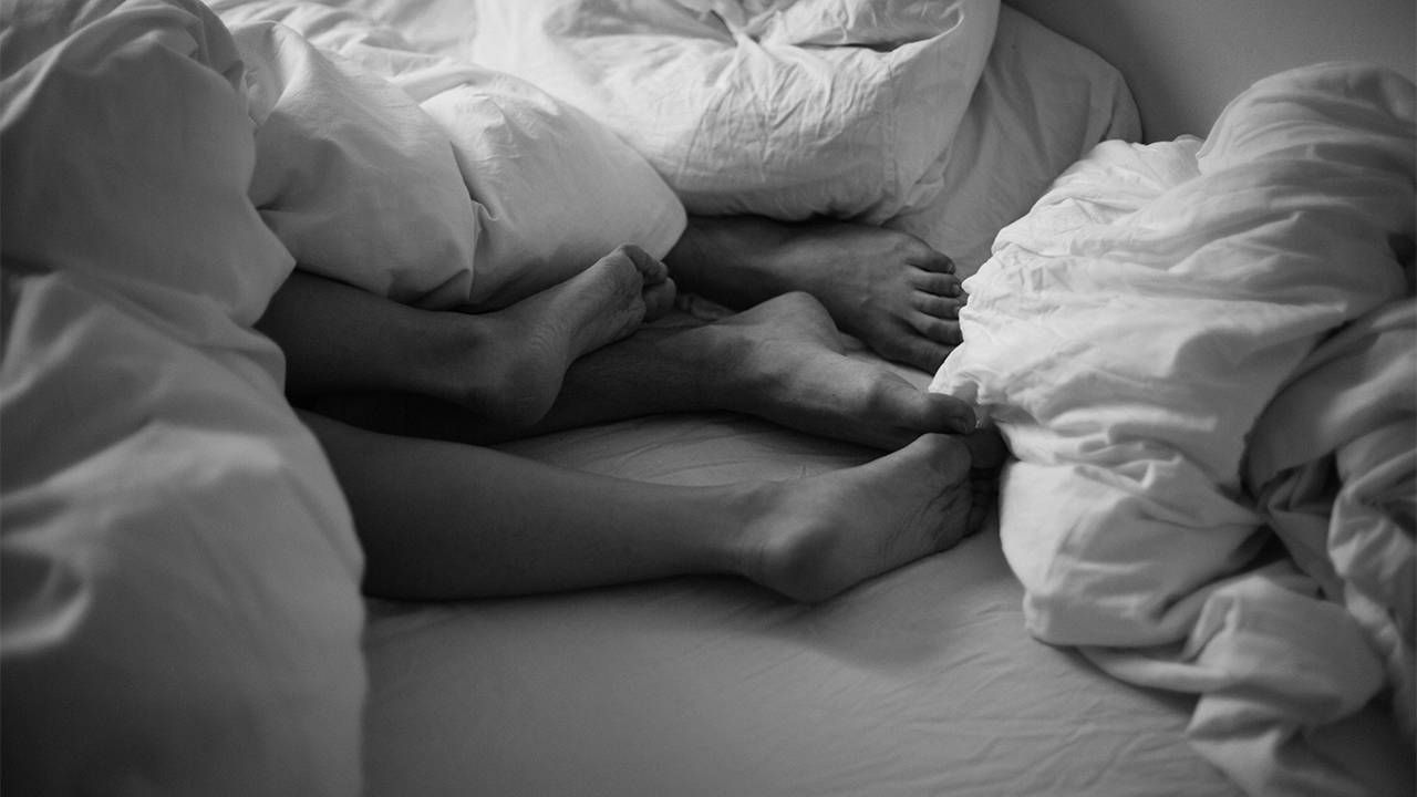 A black and white photo of a couple's feet from underneath a blanket. Next Avenue, STI STD retirement homes