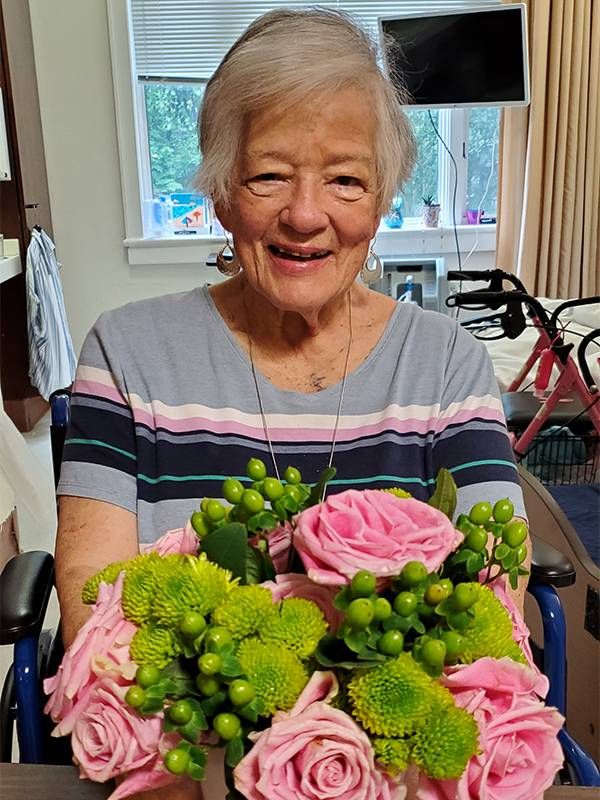 An older adult showing a vase of green and pink flowers in a vase. Next Avenue, benefits of flowers, mind and body