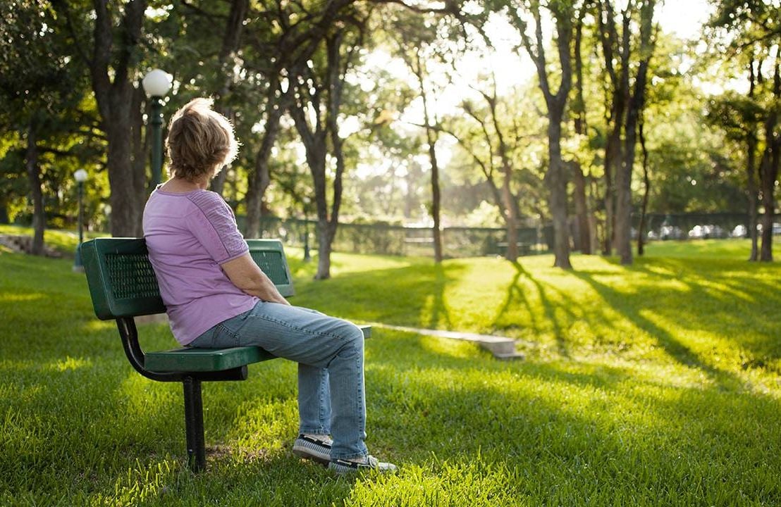 An older adult sitting on a park bench looking off into the distance. Next Avenue, husband is gay